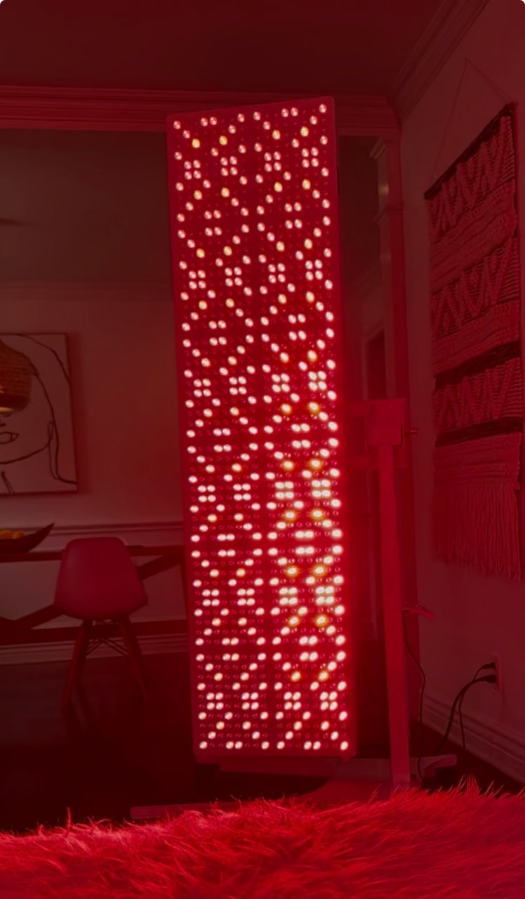 Full-Body LED Light Therapy Panel glowing red in a living room